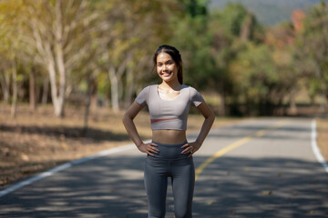 A woman is standing on a road, wearing a grey shirt and grey pants