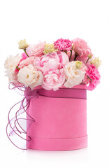Bouquet of pink peony roses in a pink round box with ribbon on a white background