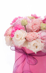 Bouquet of pink peony roses in a pink round box with ribbon on a white background