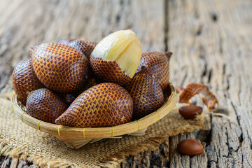 Salak (Salacca zalacca) or Snake fruits on bamboo basket and on old wood background,