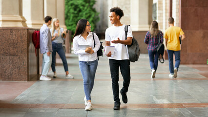 Happy diverse students walking in college campus during break and talking, copy space