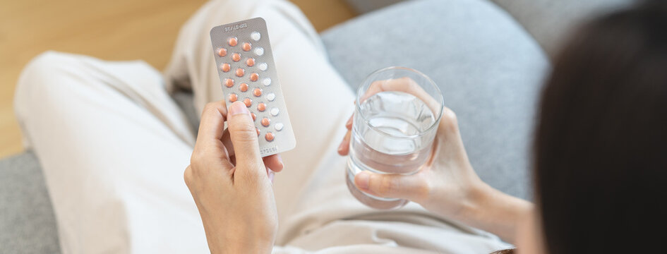 young female holding birth control pills