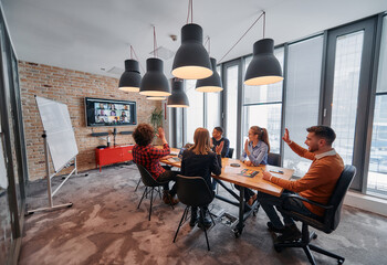 In the vibrant ambiance of a modern startup office, a diverse team of business professionals engage in discussions on various projects and develop new business strategies, epitomizing creativity and