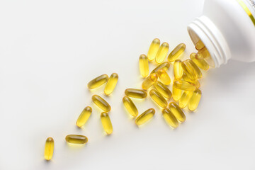 Omega 3 fish oil capsules spilling out of a bottle on a white background  top view