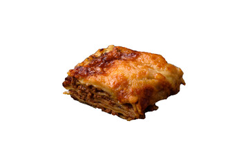 Delicious baked lasagna pasta with meat, sauce, salt, spices and herbs on a dark concrete background