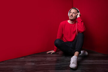young man with big white headphones listens to music and songs on a music streaming service while...