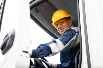 Happy driver man of industrial dump truck sits in cab and works on construction building site. © Parilov
