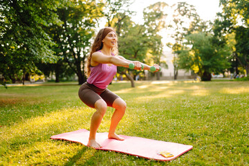 Smiling woman practicing and doing exercises on sunny day at park. Female taking care of her mental and physical health. Fitness.