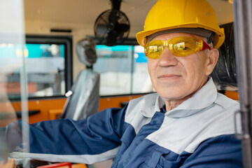 Adult man builder in hardhat operate bulldozer on mining coal, driver of excavator working at construction site