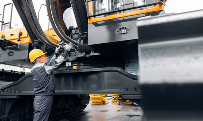 Professional mechanic diagnostics hydraulic hose system equipment on excavator to raise bucket.