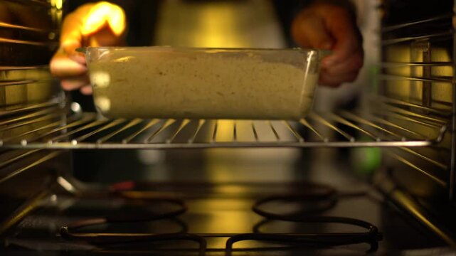 A male chef puts a cake he has prepared into the oven to bake.