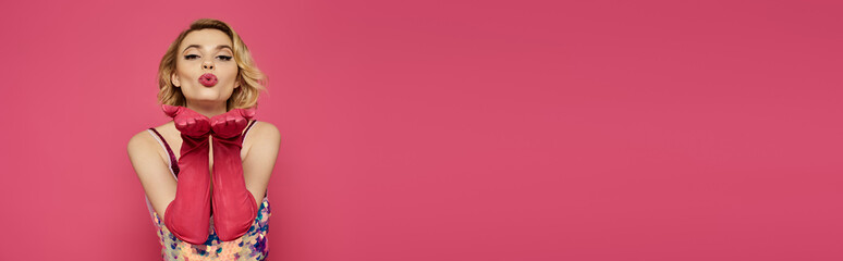 A pretty woman stands elegantly in a vibrant dress with a striking red bow on her neck.