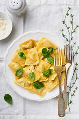 Ravioli pasta with ricotta cheese and basil on white plate served in colors of Italian flag. Traditional Italian pasta dish and recipe. Cover or article. Top view. Place for text.