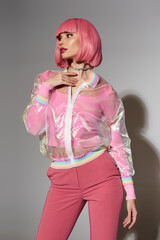 A woman with pink hair wears a transparent jacket and pink pants.