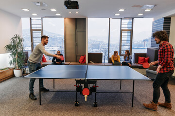  Business colleagues take a break from work to enjoy a game of table tennis, fostering teamwork and...