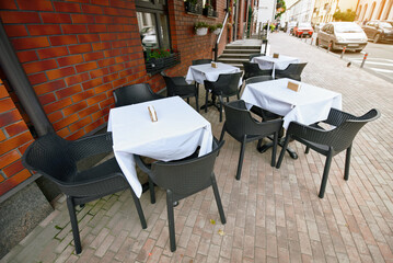 Empty street cafe terrace with tables and chairs, urban outdoor dining spaces and hospitality decor. Urban restaurant terrace with empty tables and chairs. Street terrace, outdoor dining area