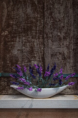 Dettaglio di un vaso con una pianta dai fiori viola sul davanzale di una finestra chiusa