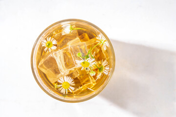 Herbal flower daisy chamomile ice tea, infused aromatic cold drink with daisy camomile wildflower and ice cubes, copy space