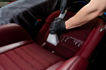 Cleaning car backseat with special vacuum nozzle. Detailing car seats with the help of vacuum...