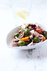 Salad with tuna, green olives and cherry tomatoes. Bright wooden background. Close up. Copy space.	