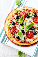 Pizza with salami, jalapeno pepper and black olives. Home made food. Concept for a tasty and hearty meal. Close up.	