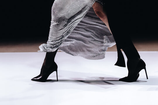 Fashion beauty details of a long silver skirt and black high heels on a black white background. Fashion model walking the runway on Fashion week