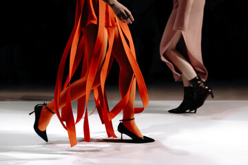 Cropped figures of fashion models women wearing creative orange skirt and beige dress. Stylish...