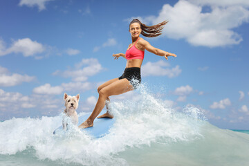 Naklejka premium Female surfer with a dog riding a surfboard on a wave