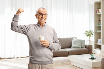 Elderly man holding a glass of milk and showing arm muscle