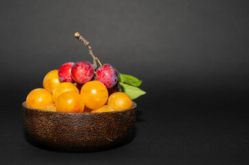 Delicious red and yellow plums on a black background. Copy space.
