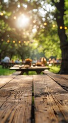 Empty wooden table and blurred view of friends cooking food on barbecue grill in park