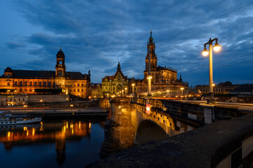 Obraz premium Night shot of the brightly lit skyline of the historic old town of Dresden with the River Elbe in the foreground.