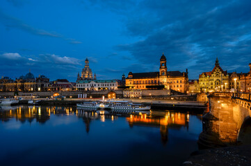 Night shot of the brightly lit skyline of the historic old town of Dresden with the River Elbe in the foreground.