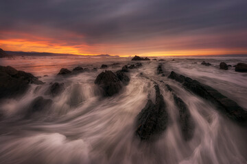 Sunset on Barrika beach, Bizkaia, with the waves entering with force among the flysch