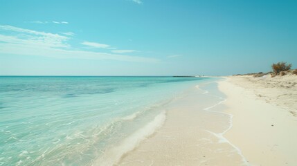 A tranquil image of a pristine beach with clear turquoise waters, gentle waves lapping onto the soft white sand, and a bright blue sky with few wispy clouds.
