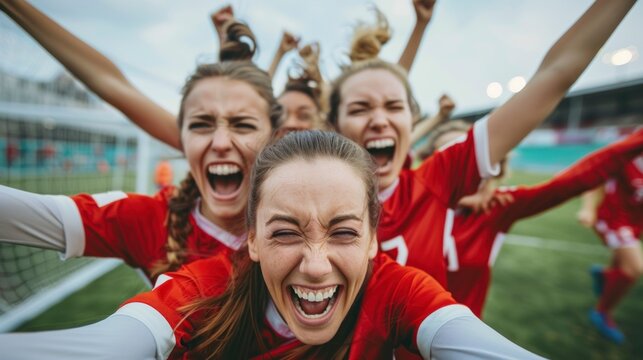 group of happy female soccer players in uniform celebrating a goal on the field