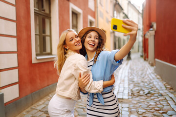 Portrait of funny pretty best friends women having fun making selfie at city center, positive crazy...