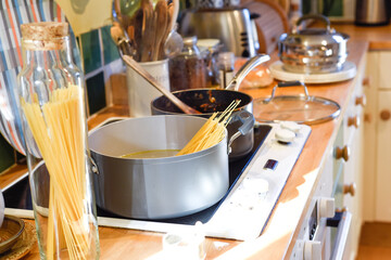 Cooking pasta in a home kitchen interior the pan has boiling water to cook spaghetti and raw ingredients on the kitchen counter