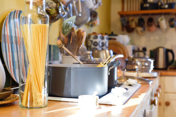 Cooking pasta in a home kitchen interior the pan has boiling water to cook spaghetti and raw ingredients on the kitchen counter