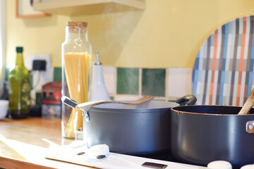 Cooking pasta in a home kitchen interior the pan has boiling water to cook spaghetti and raw ingredients on the kitchen counter