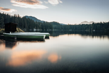 Ruhiger Bergsee mit Booten und Wolken