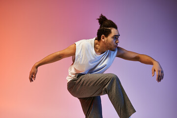 A young African American man dances with expression on a gradient background of orange and purple.