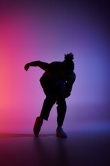 Silhouetted African American man dances energetically against vibrant background, showcasing contemporary movement.