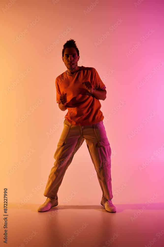 Wall mural A young African American man dances against a vibrant gradient background.