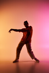 An African American male dancer poses in front of a vibrant gradient background, showcasing his dynamic moves.