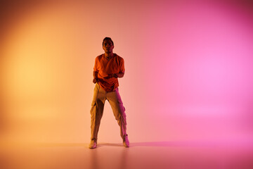 A young African American man dances against a vibrant gradient background.