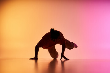A young African American man dances on a vibrant gradient background.