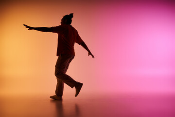 A young African American man dances in silhouette against a backdrop of a colorful gradient.