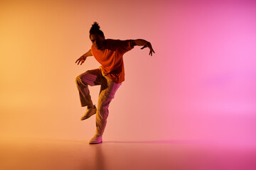 A young African American man dances in front of a colorful gradient background, showcasing his impressive skills and passion.