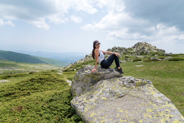 Traveler Woman sitting on a rock in the  summer mountain  .Vitosha Mountain ,Bulgaria 